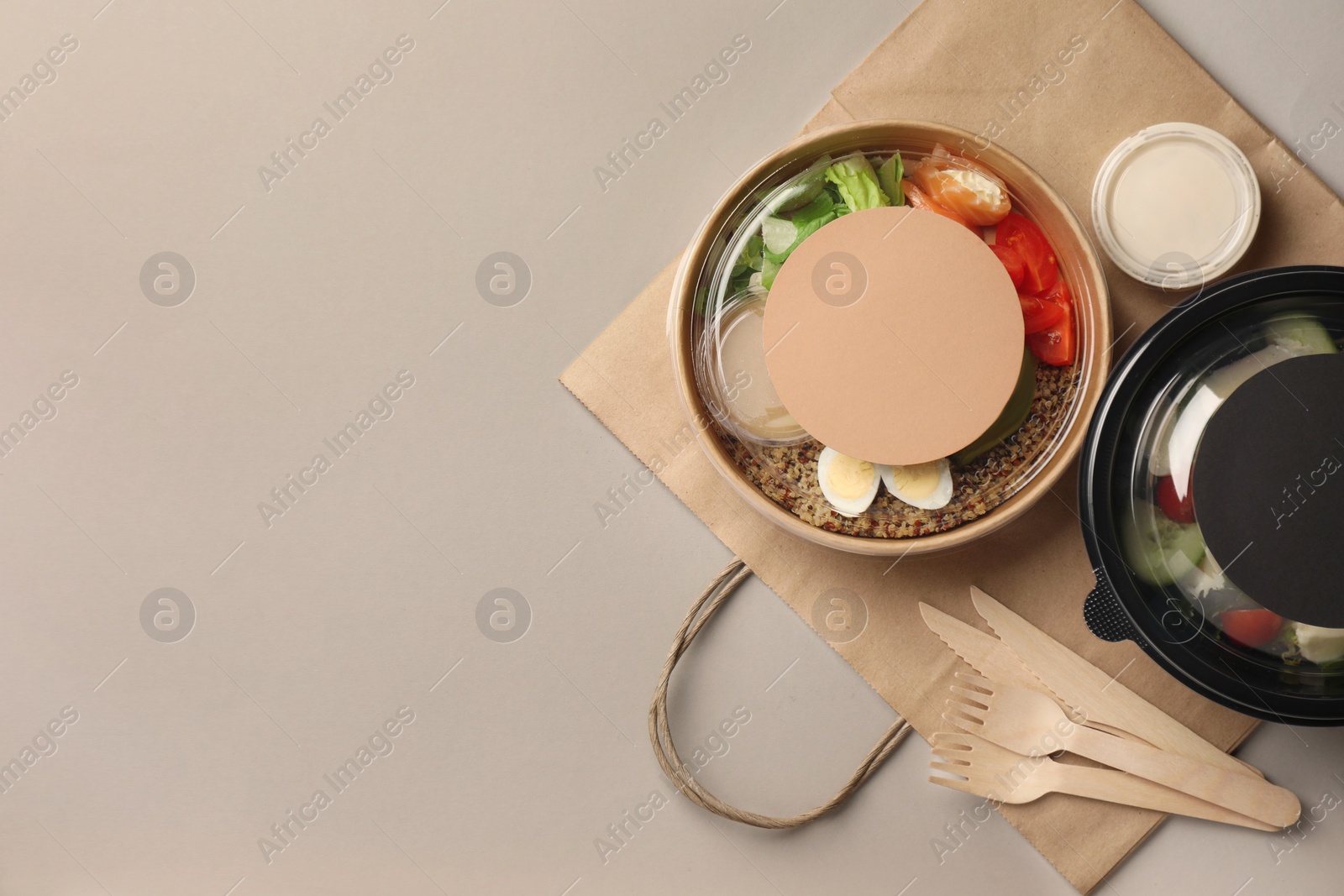 Photo of Tasty food in containers with wooden knives and forks on light grey table, flat lay. Space for text