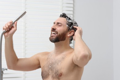 Happy man washing his hair with shampoo in shower