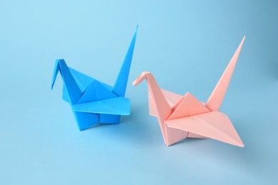 Origami art. Colorful handmade paper cranes on light blue background