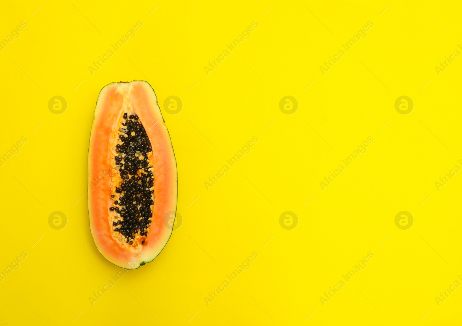 Photo of Fresh juicy halved papaya on yellow background, top view. Space for text