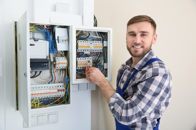 Photo of Electrician repairing fuse box with screwdriver indoors