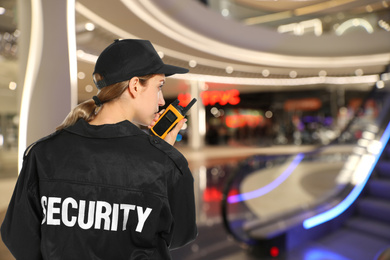 Security guard using portable radio transmitter in modern shopping mall, space for text