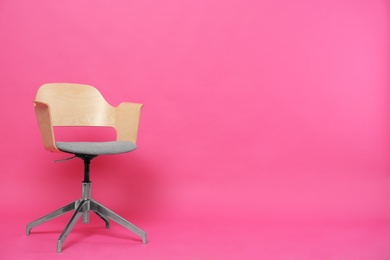 Photo of Comfortable office chair on pink background, space for text