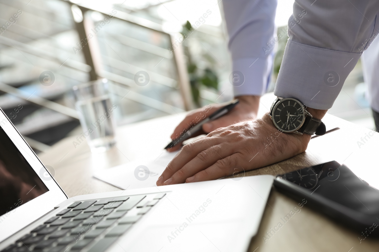 Photo of Businessman working with documents at wooden desk in office, closeup