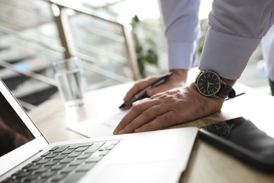 Businessman working with documents at wooden desk in office, closeup