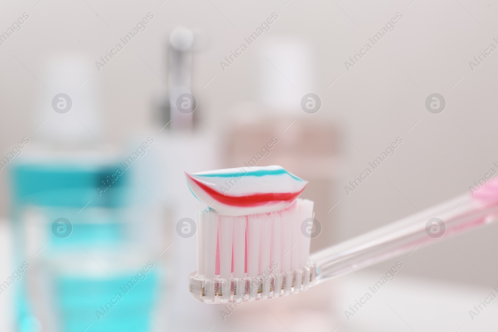 Photo of Toothbrush with paste near mouthwash on blurred background, closeup