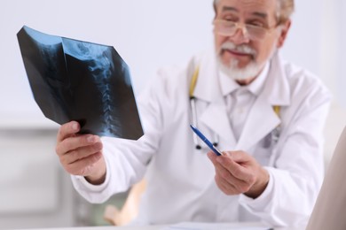 Photo of Professional orthopedist with X-ray picture in clinic