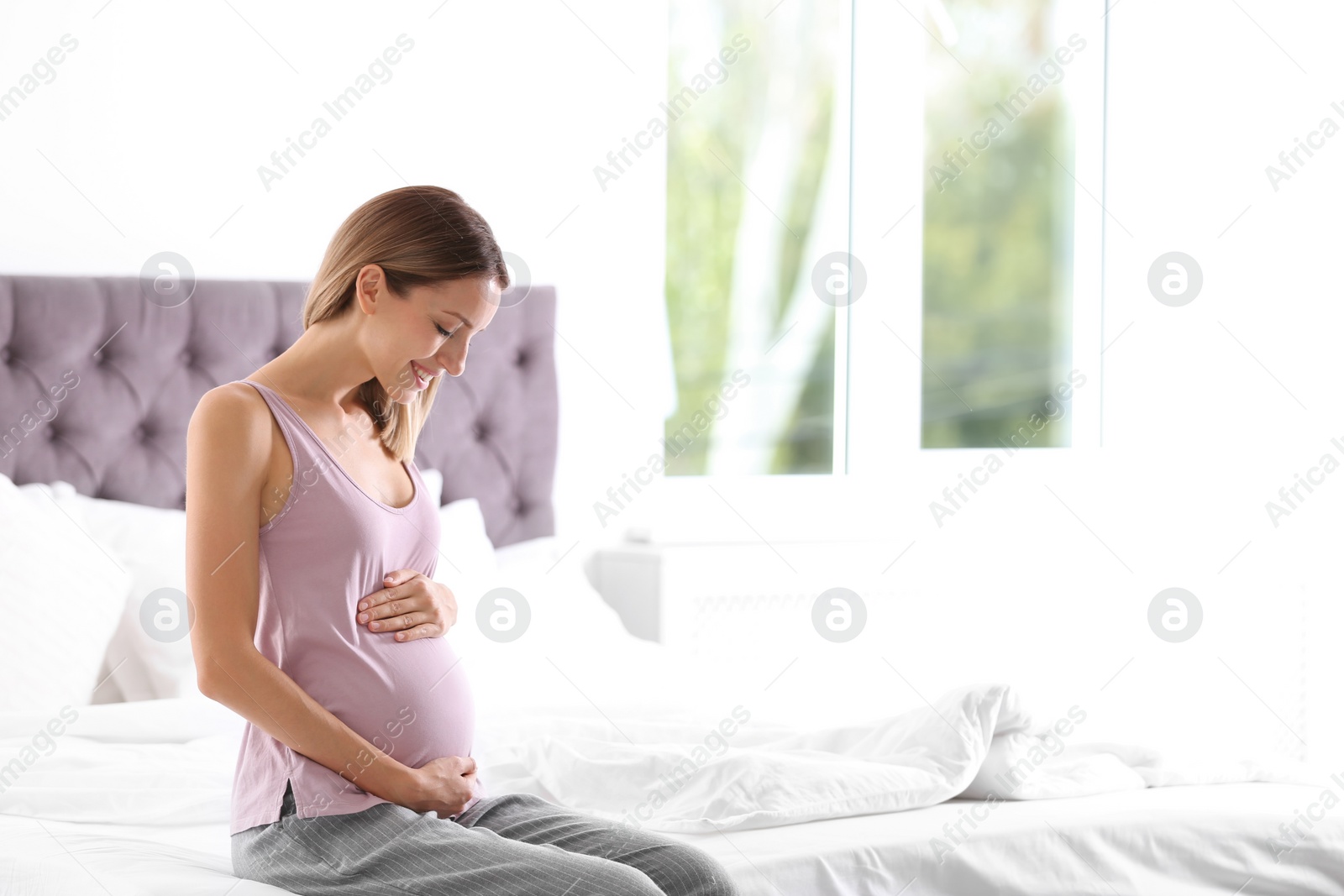 Photo of Happy pregnant woman sitting in bed at home