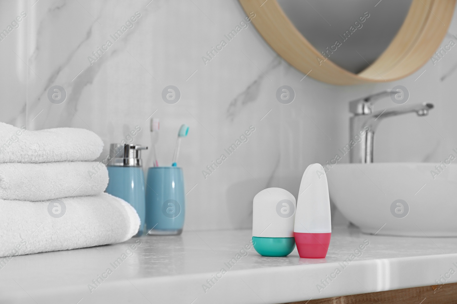 Photo of Different deodorants on light countertop in bathroom