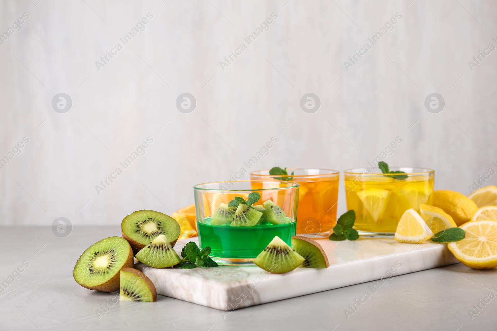 Photo of Glasses of tasty jelly served on light table. Space for text