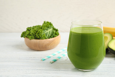 Tasty fresh kale smoothie on white wooden table