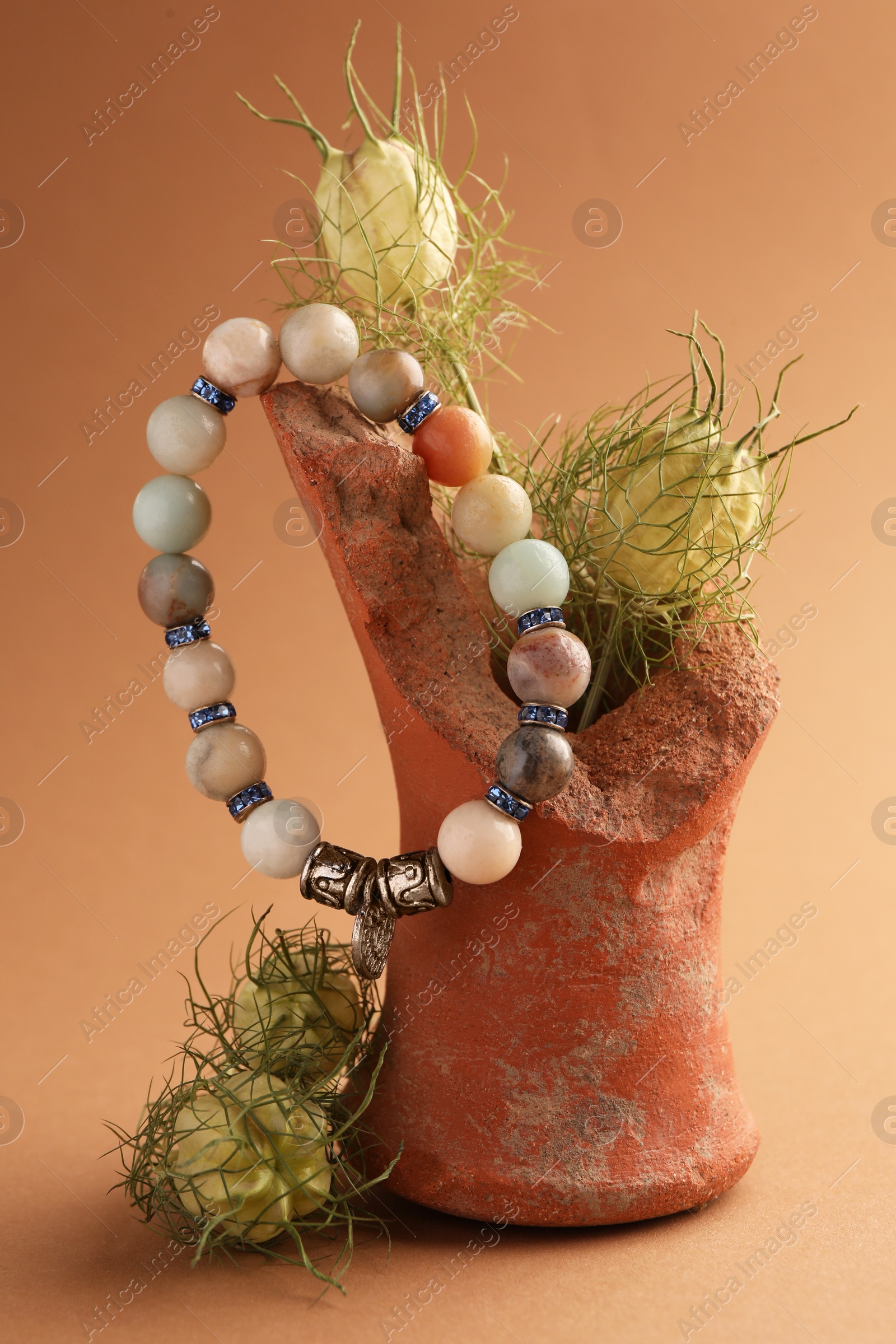 Photo of Stylish presentation of beautiful bracelet with gemstones on light brown background