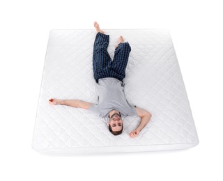 Young man lying on mattress against white background, above view