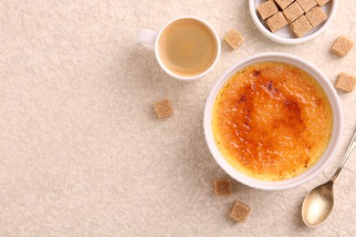 Photo of Delicious creme brulee in bowl, sugar cubes, coffee and spoon on light textured table, flat lay. Space for text