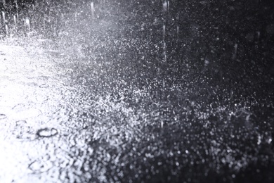 Photo of Rain drops falling down against dark background