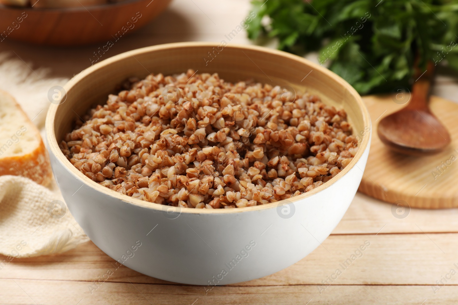 Photo of Tasty buckwheat in bowl on wooden table, closeup