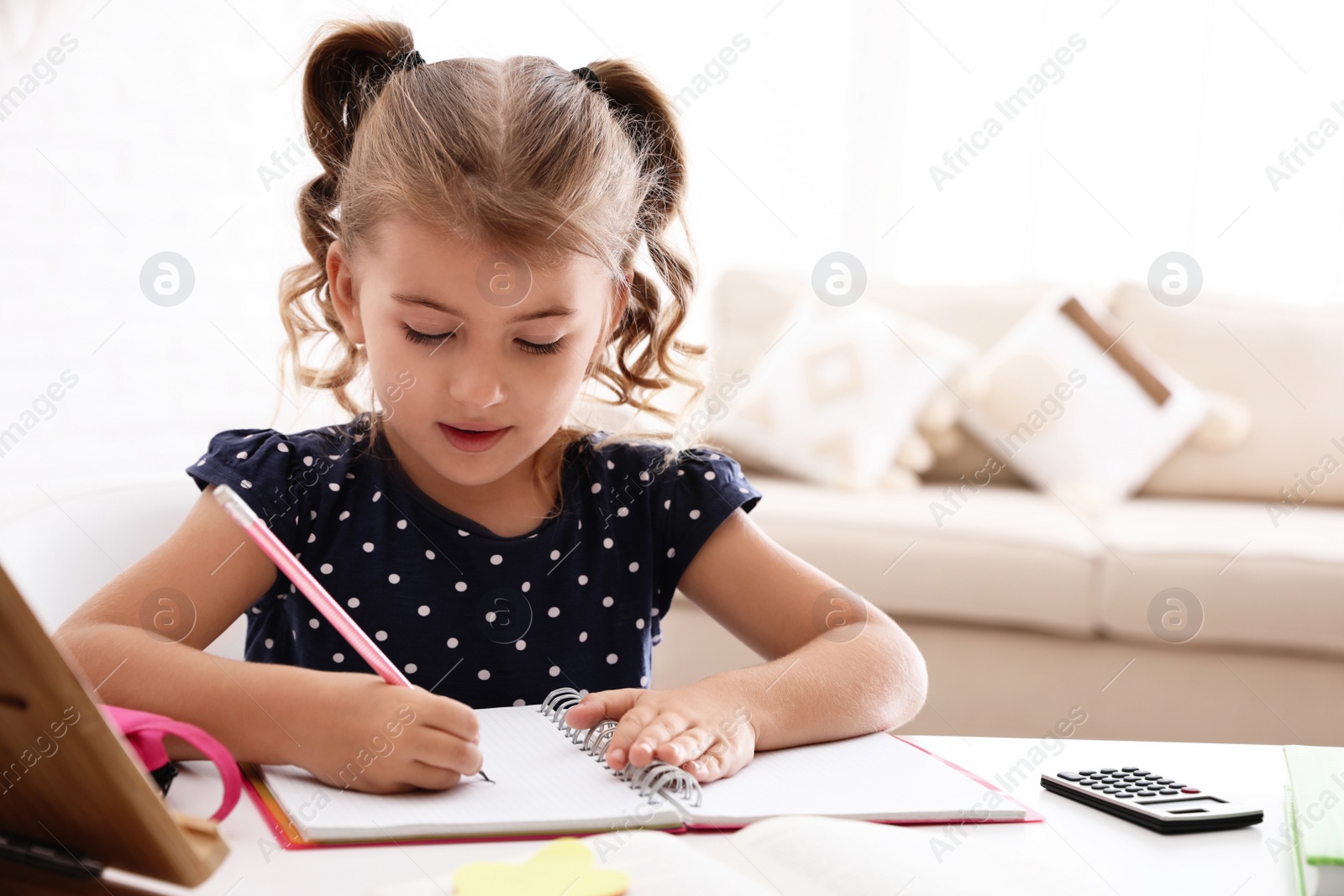 Photo of Cute little girl doing homework at table