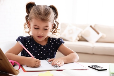 Photo of Cute little girl doing homework at table