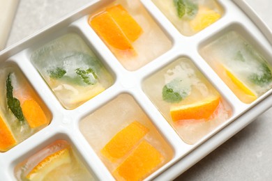 Ice cubes with orange and mint on light table, closeup