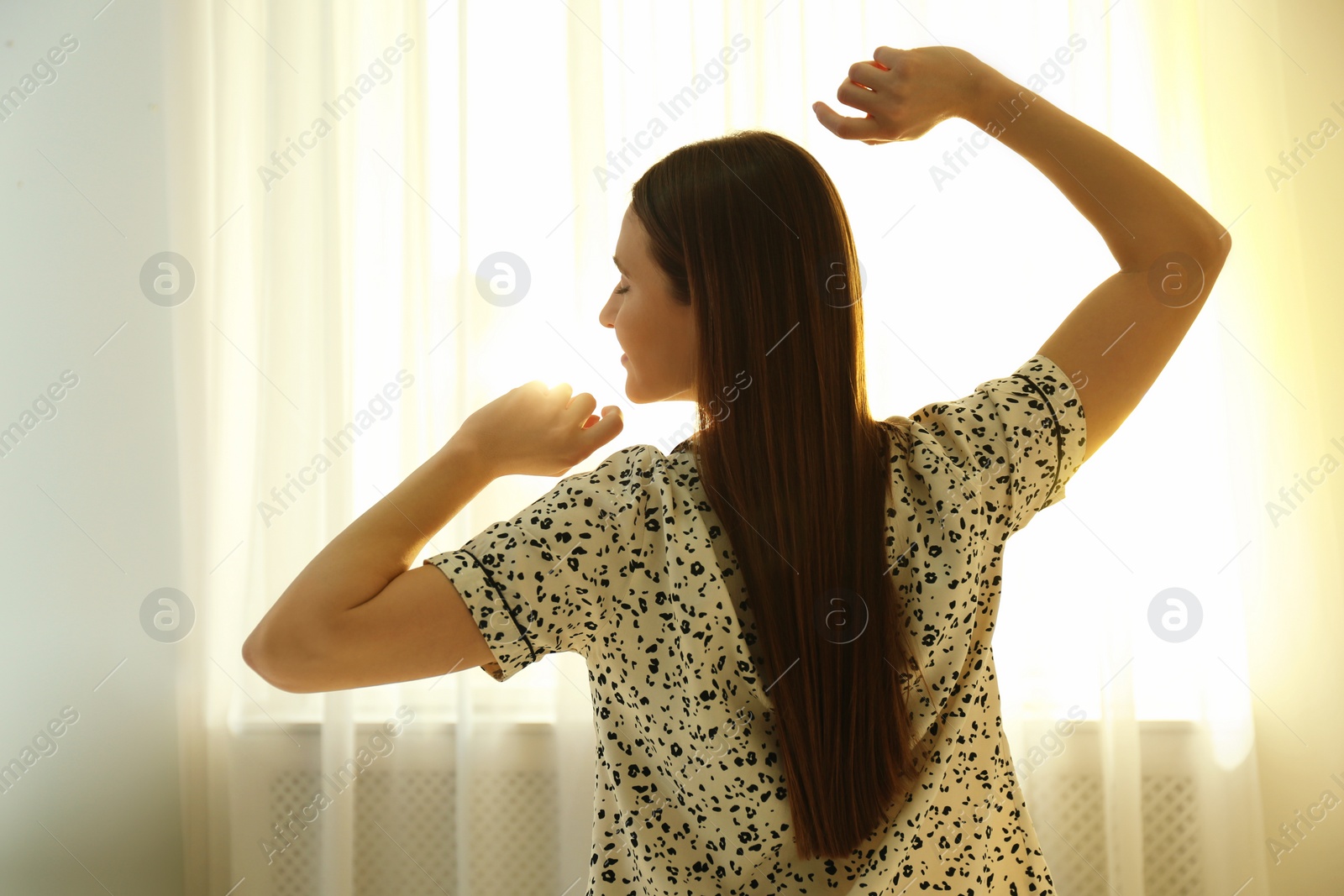 Photo of Young woman stretching on bed at home. Lazy morning