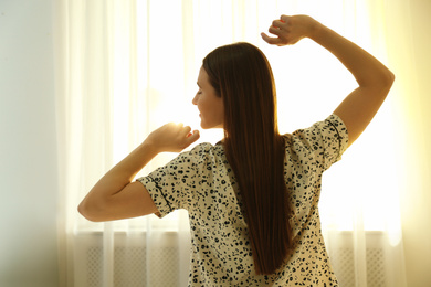 Young woman stretching on bed at home. Lazy morning