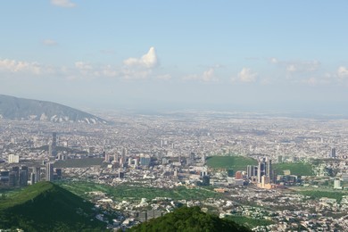 Photo of Picturesque view of trees, buildings and mountains under beautiful sky in city