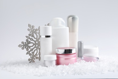 Photo of Set of cosmetic products and decorative snow on white background. Winter care
