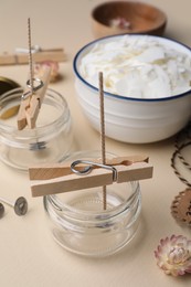 Photo of Glass jars with wicks and clothespins as stabilizers on beige background. Making homemade candles