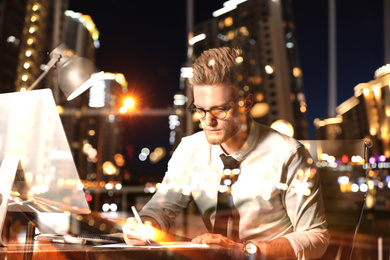 Image of Double exposure of young man working in office and night cityscape. Financial analytics