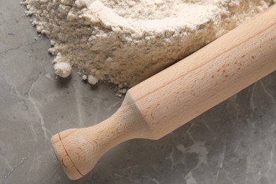 Photo of Pile of flour and rolling pin on grey marble table, top view