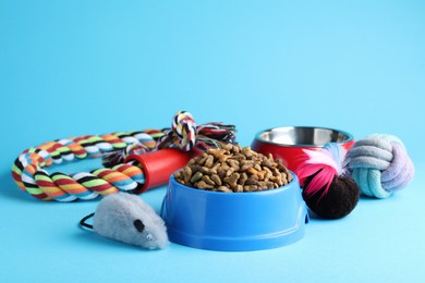 Feeding bowls and toys for pet on light blue  background