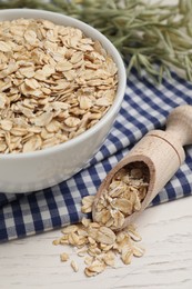 Photo of Bowl and scoop with oatmeal on white wooden table, closeup