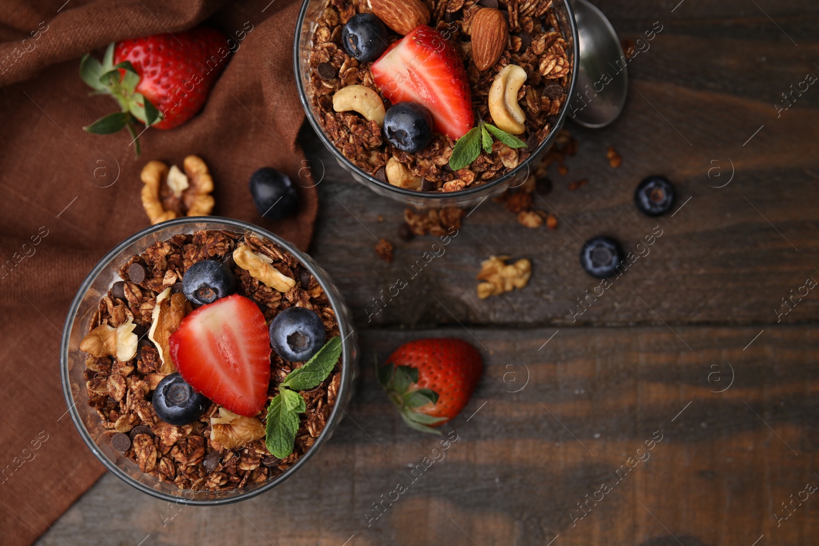 Photo of Tasty granola, berries and nuts on wooden table, top view. Space for text