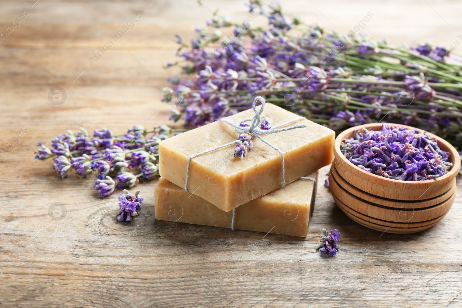 Photo of Handmade soap bars with lavender flowers on brown wooden table. Space for text