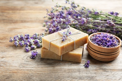 Photo of Handmade soap bars with lavender flowers on brown wooden table. Space for text