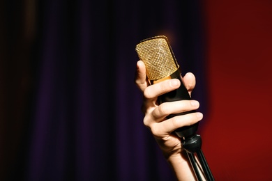 Photo of Woman holding microphone on color background, closeup. Space for text