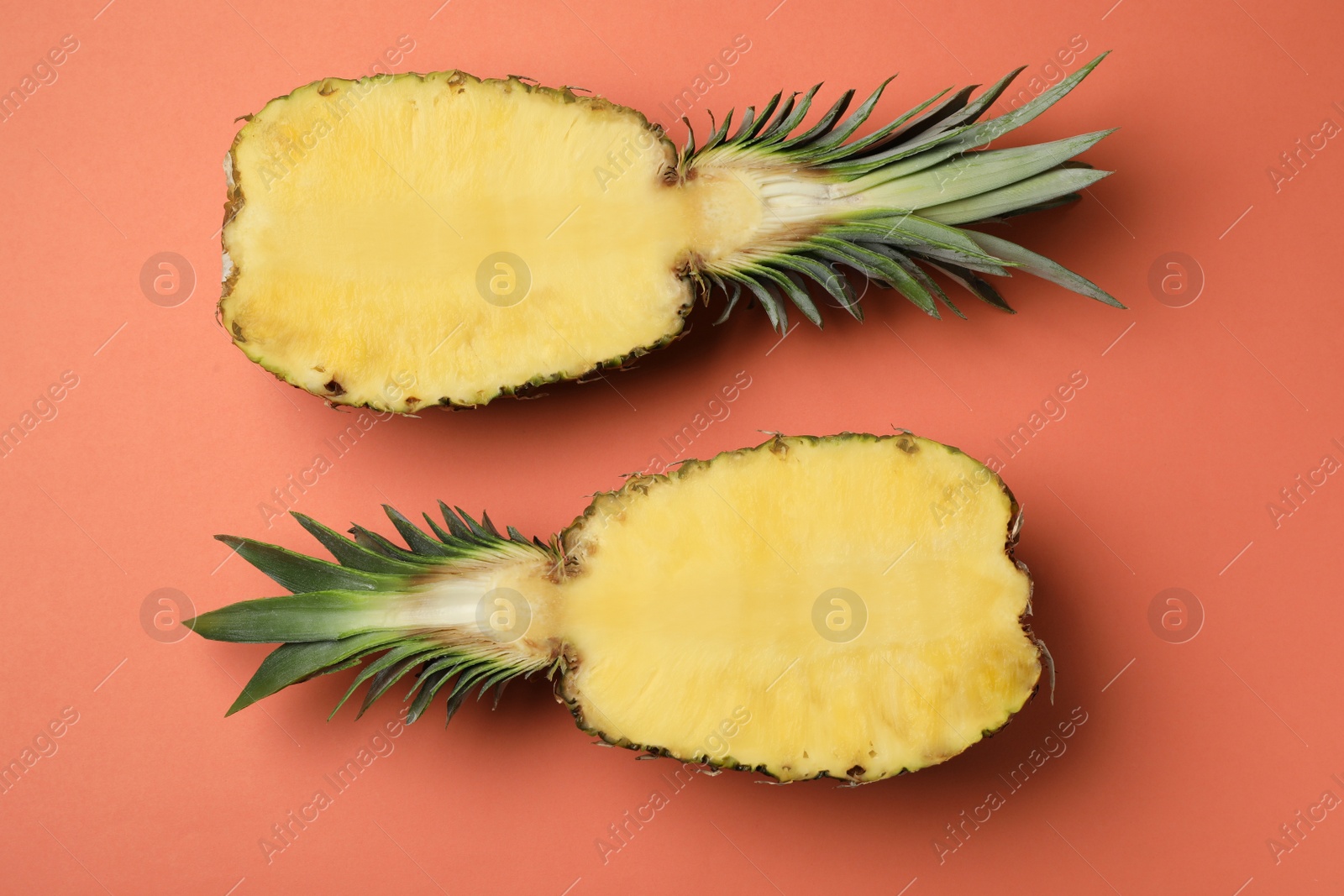 Photo of Halves of fresh pineapple on orange background, top view