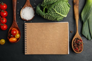 Photo of Recipe book and different ingredients on black table, flat lay with space for text. Cooking classes