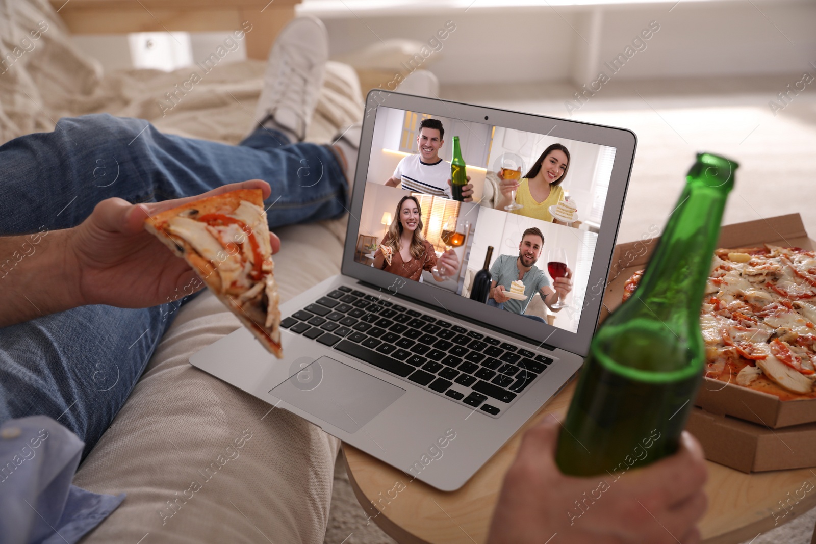 Image of Man with bottle of beer and pizza having online party via laptop at home during quarantine lockdown, closeup