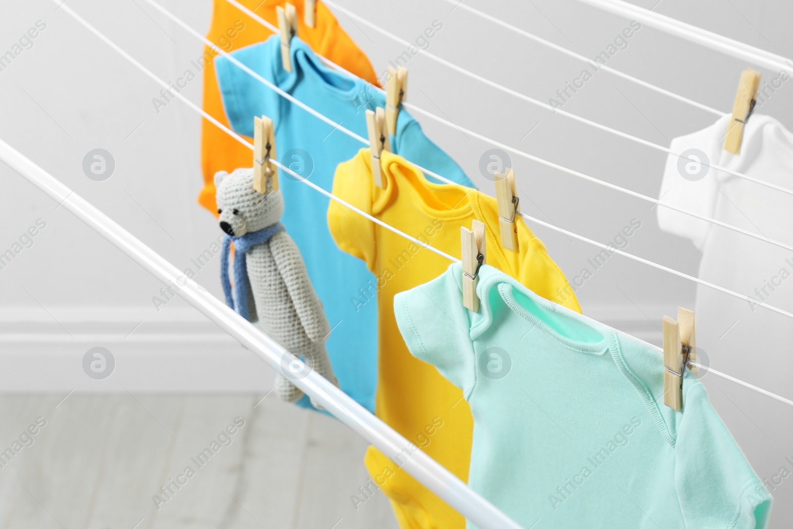 Photo of Different cute baby onesies and toy bear hanging on clothes line. Laundry day