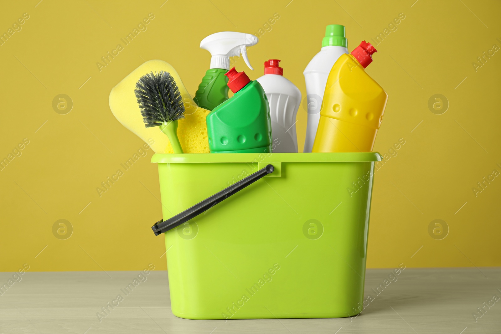 Photo of Bucket with cleaning products on grey table