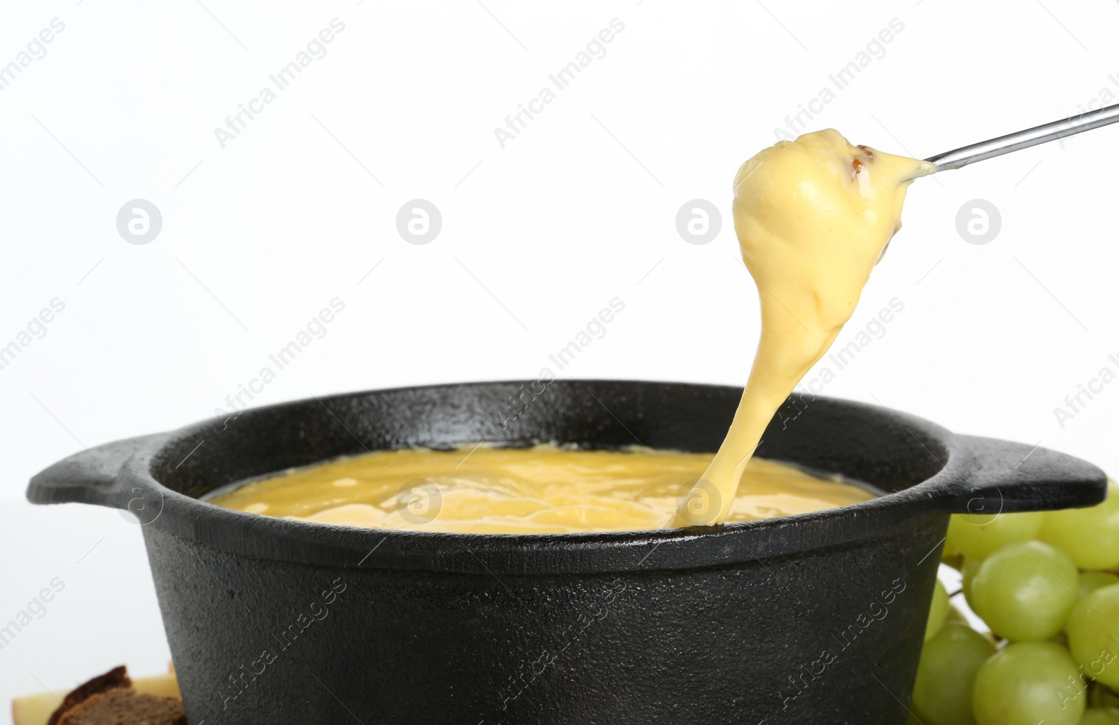 Photo of Dipping piece of bread into fondue pot with tasty melted cheese isolated on white