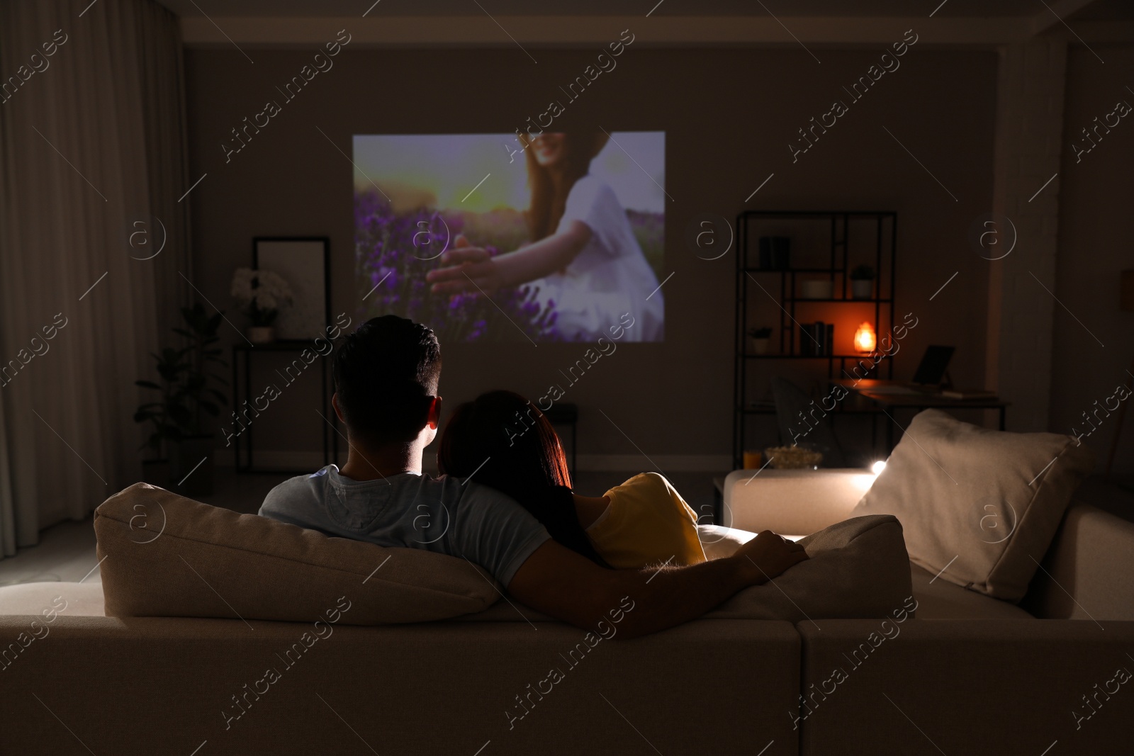 Photo of Couple watching movie on sofa at night, back view. Space for text