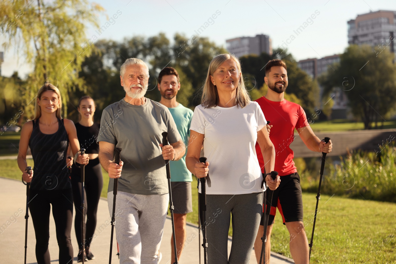 Photo of Group of happy people practicing Nordic walking with poles in park