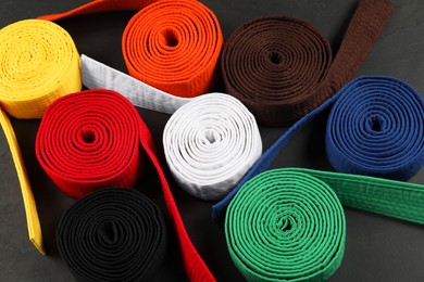 Photo of Colorful karate belts on gray background, above view