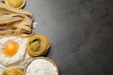 Photo of Flat lay composition with different types of pasta on grey table. Space for text