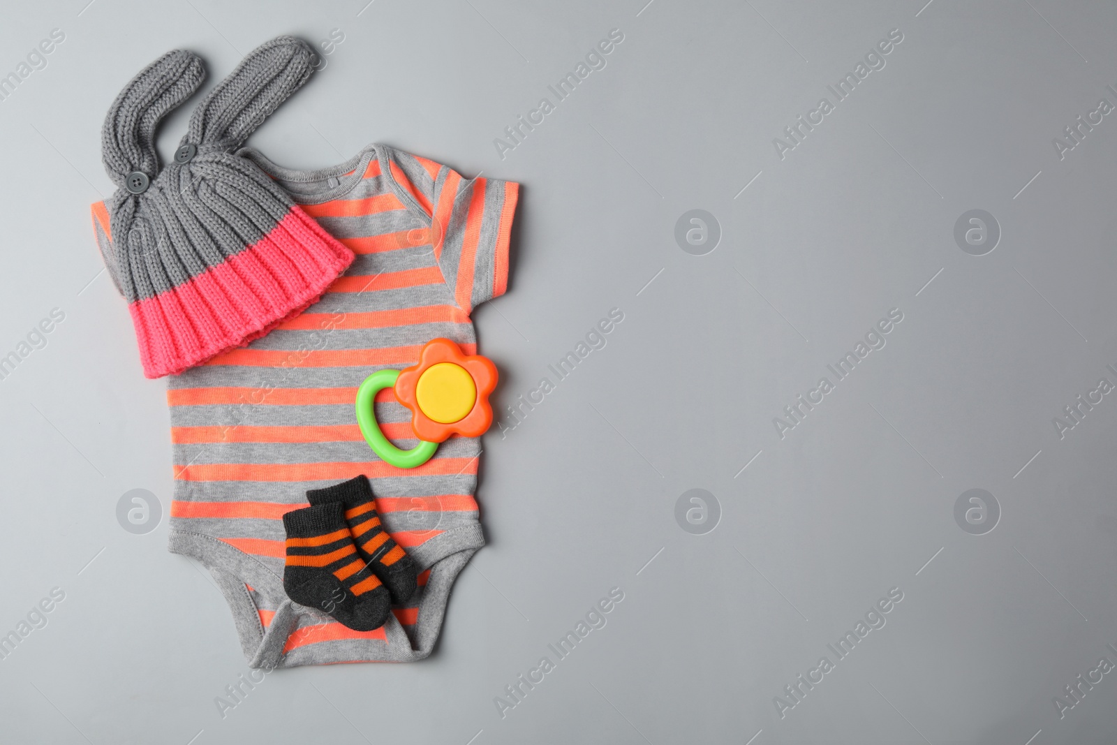 Photo of Flat lay composition with child's clothes and teether on grey background, space for text