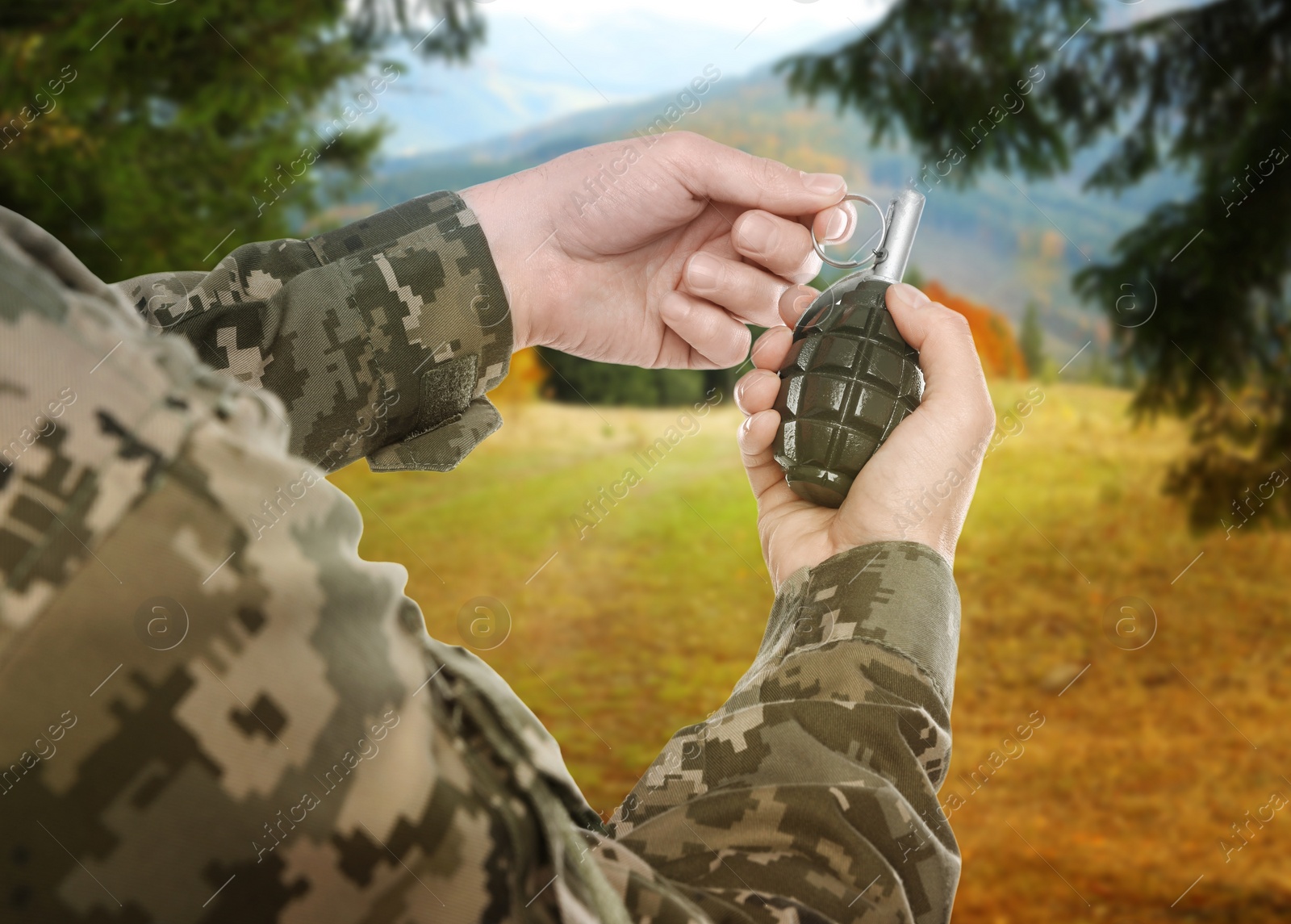 Image of Soldier pulling safety pin out of hand grenade outdoors, closeup