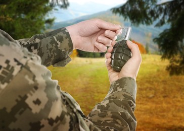 Soldier pulling safety pin out of hand grenade outdoors, closeup