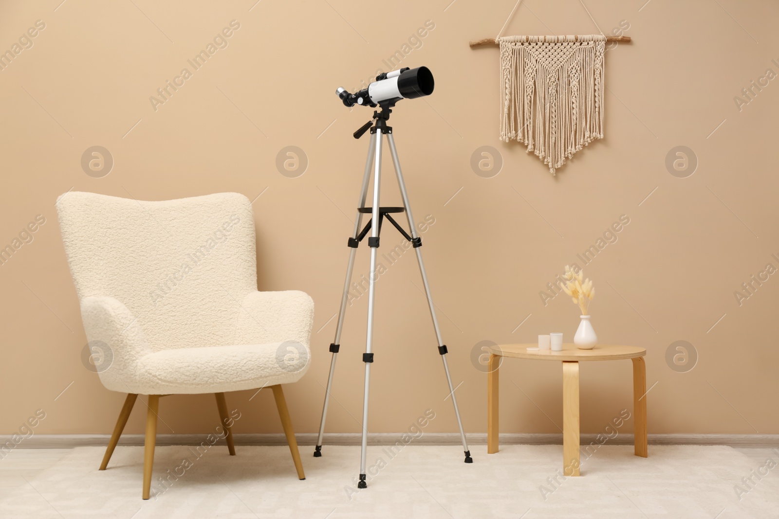 Photo of Tripod with modern telescope in stylish room